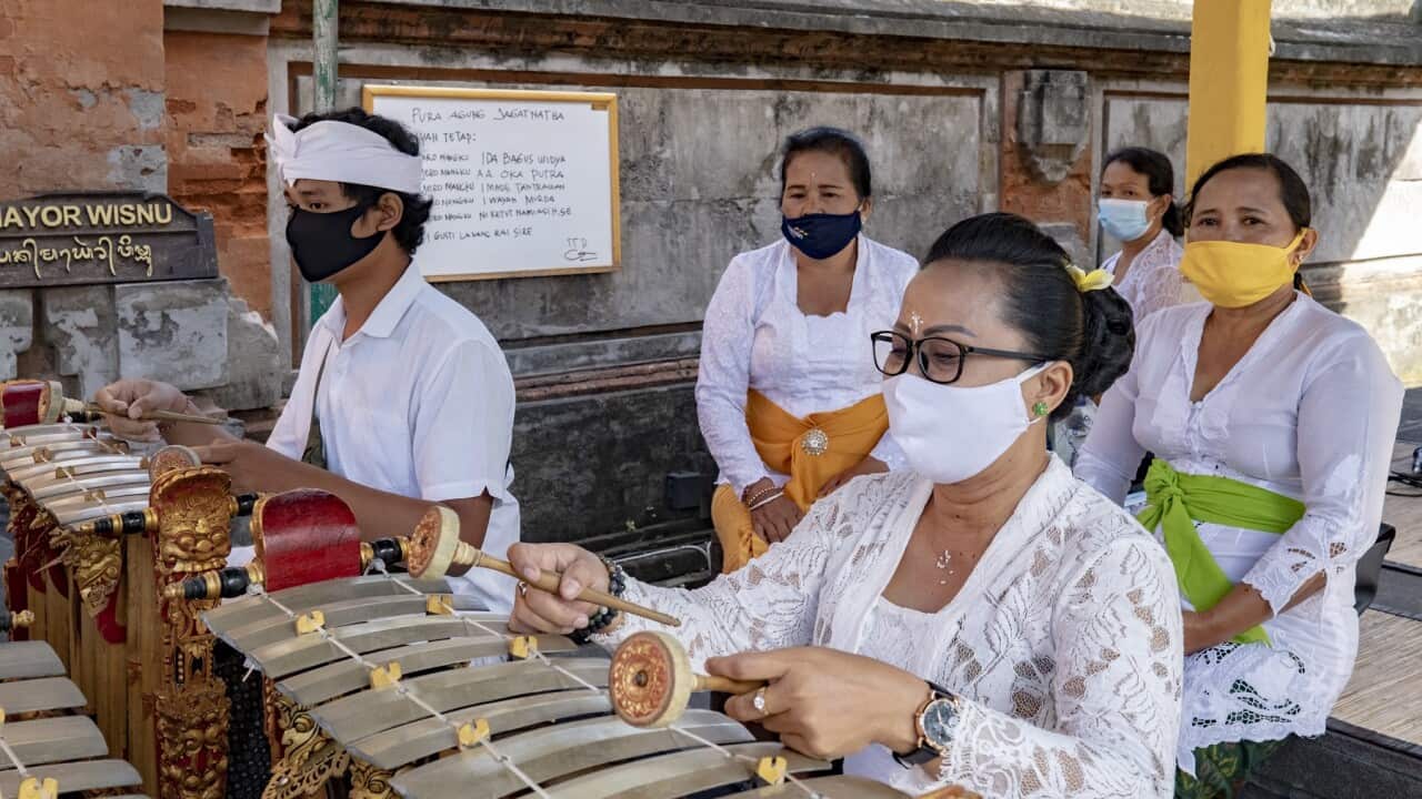Balinese wear face masks as they play traditional music while participating in a Saraswati ceremony at a temple in Bali.