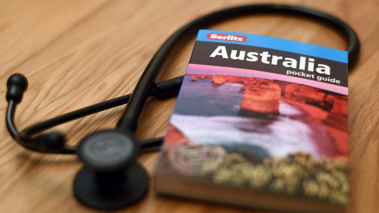 A doctor's stethoscope lies next to a guide book to Australia.