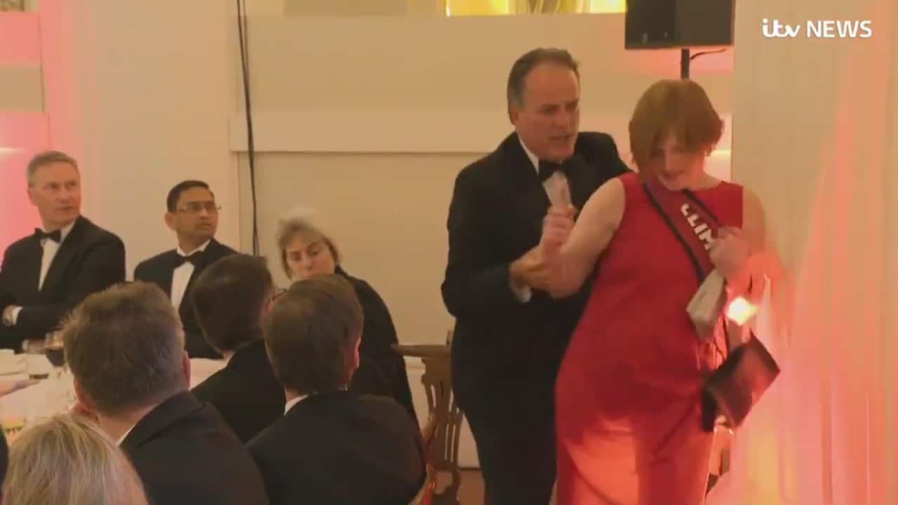 British MP Mark Field restrains a climate protester at an official dinner held at London's Mansion House.