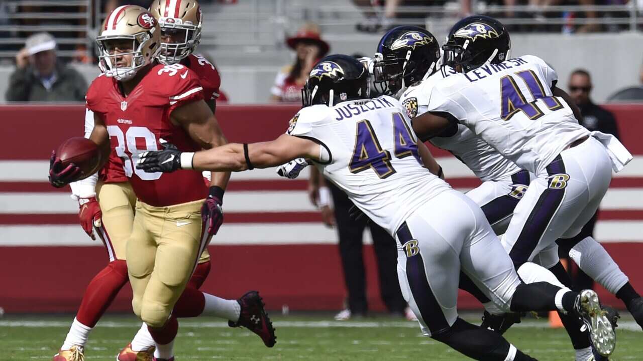 San Francisco 49ers kick return Jarryd Hayne of Australia tries to elude a tackle by Baltimore Ravens fullback Kyle Juszczyk and Baltimore Ravens cornerback Anthony Levine