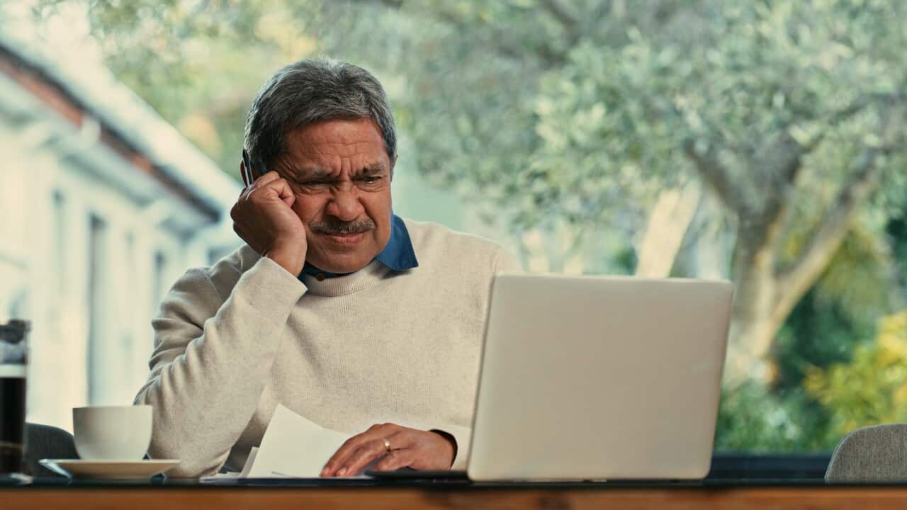 Shot of a senior man using a laptop and going through paperwork at home