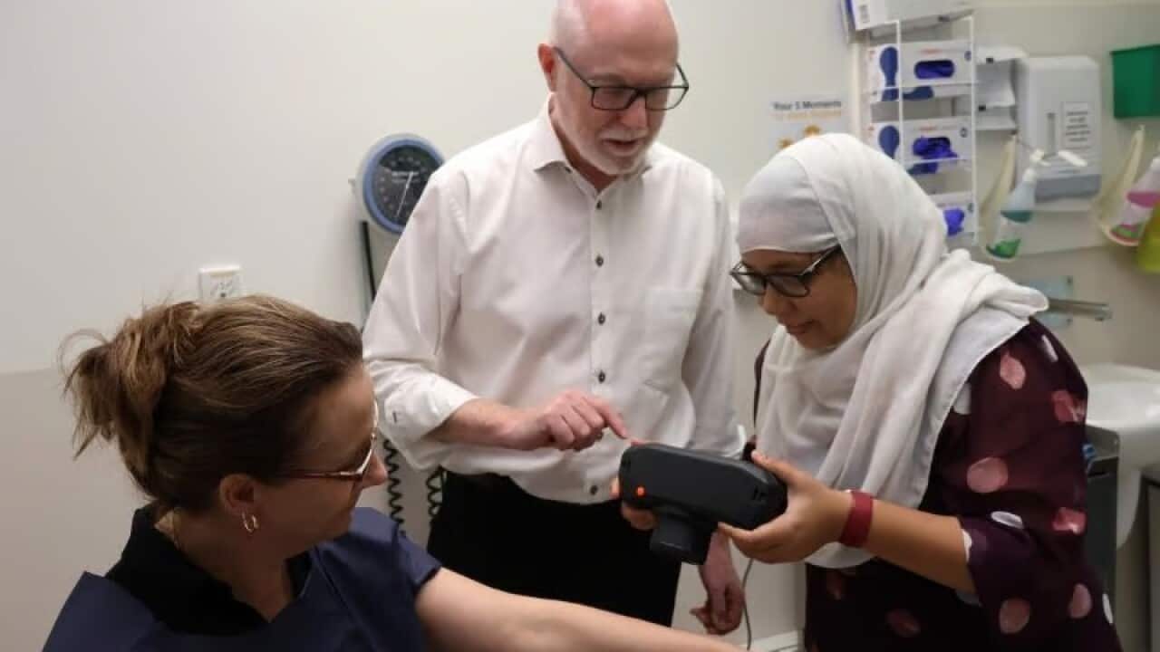 picture of two women and a man in a clinic looking at  camera 