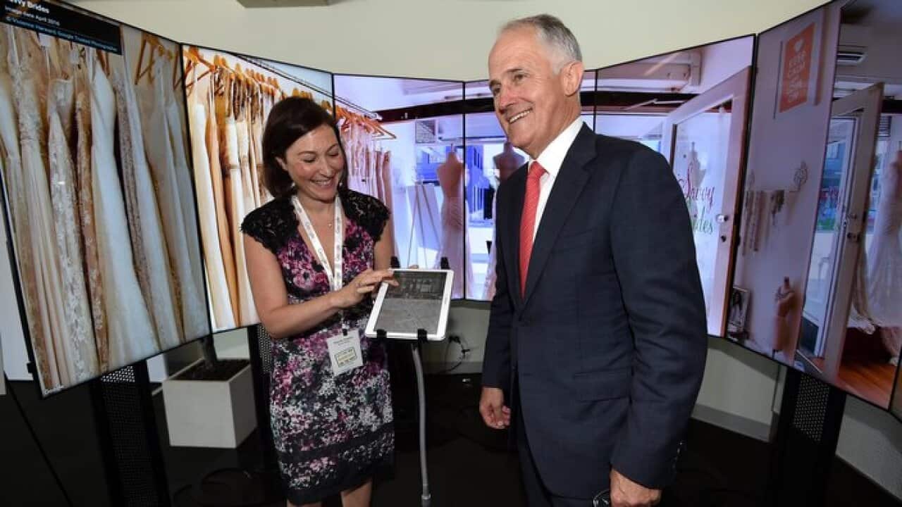 Australian Prime Minister Malcolm Turnbull looks at an interactive display for a bridal dress store, with owner Mandy Daddia, as he attends the Google Australia small business roadshow at North Bondi surf club, in Sydney, Friday, April 22, 2016.