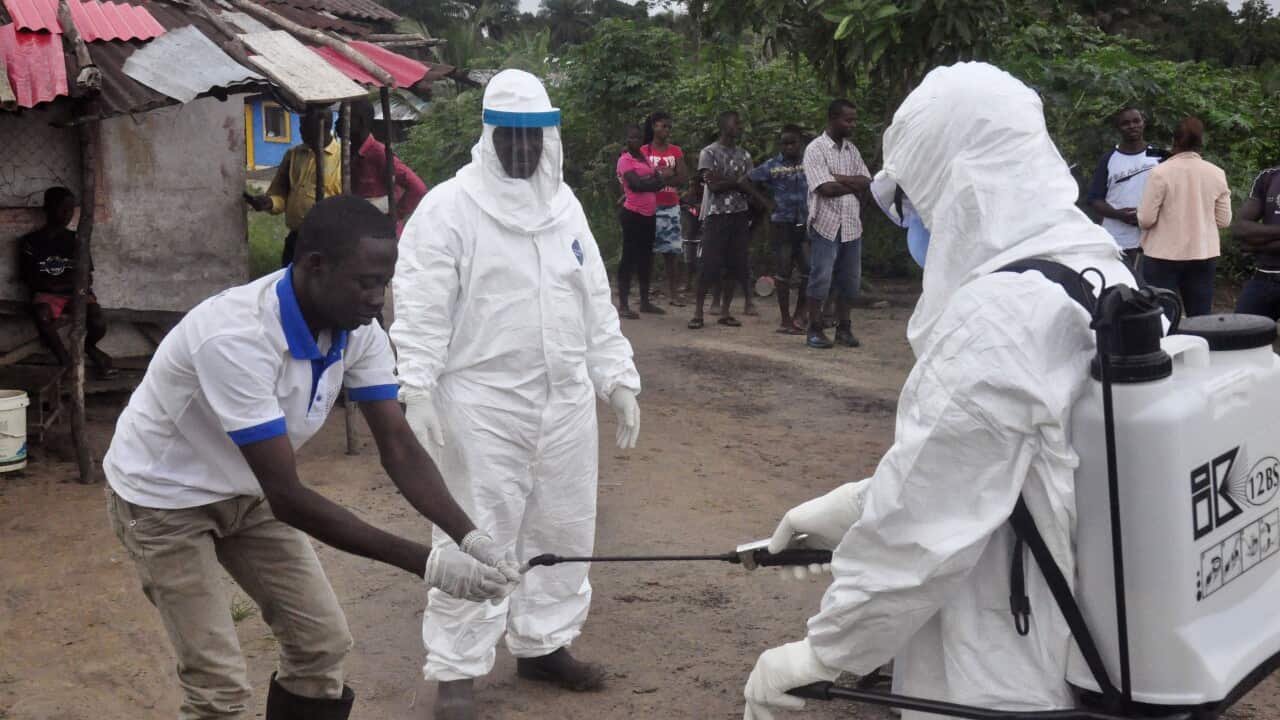 Ebola health workers wash their hands in an area where a 17-year old boy died from the virus near Monrovia, Liberia, June 30, 2015. (AP Photo/ Abbas Dulleh)
