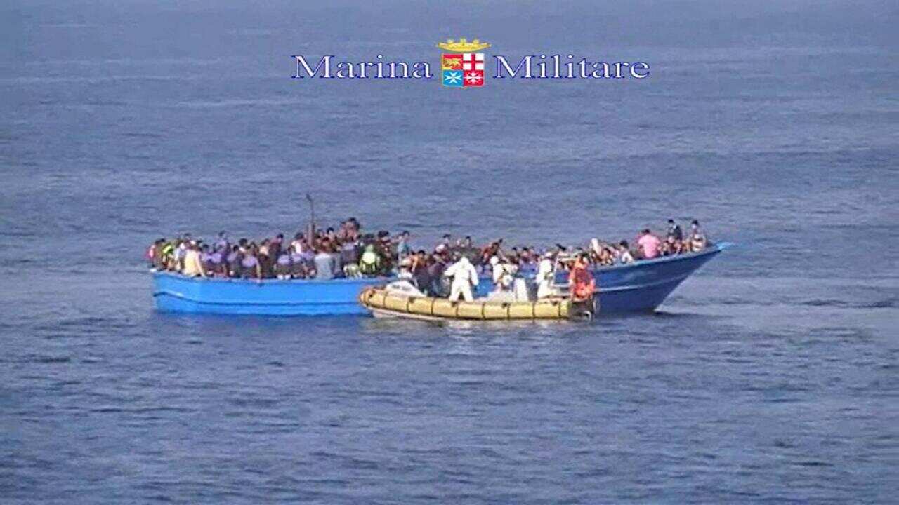 This image taken from video provided by the Italian Navy (Marina Militare) Saturday, Aug. 15, 2015, shows an Italian Navy RIB approaching a fishing boat crowded with migrants off the coast of Libya. (Marina Militare via AP)