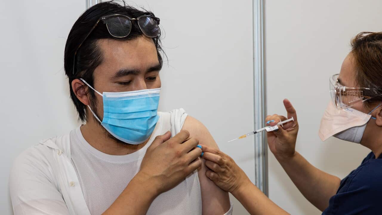 A health worker administering a COVID-19 vaccine into a man's arm.