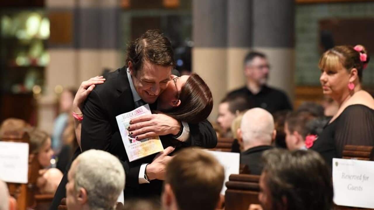 Samuel Johnson hugs a supporter at a memorial service.