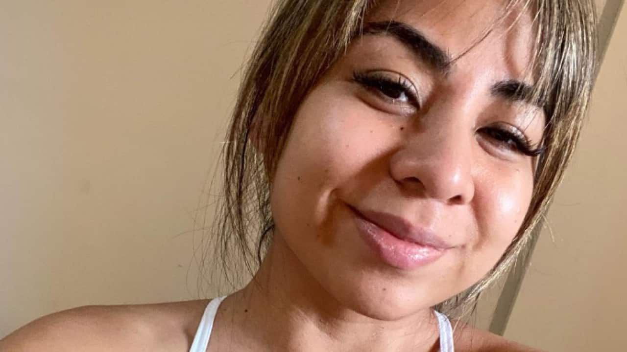 A woman wearing a bikini top smiles at the camera.