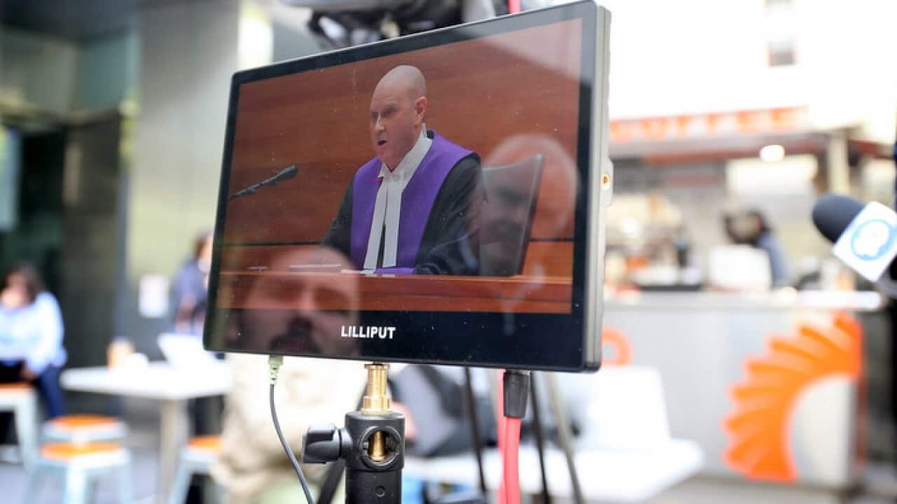 Chief Judge Peter Kidd's sentencing of Cardinal George Pell seen on a TV monitor outside Melbourne County Court