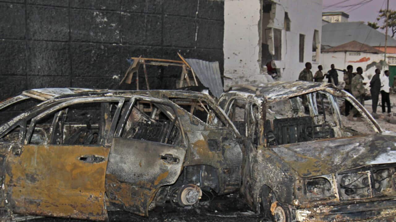 Somali soldiers stand near the scene of a car bomb attack