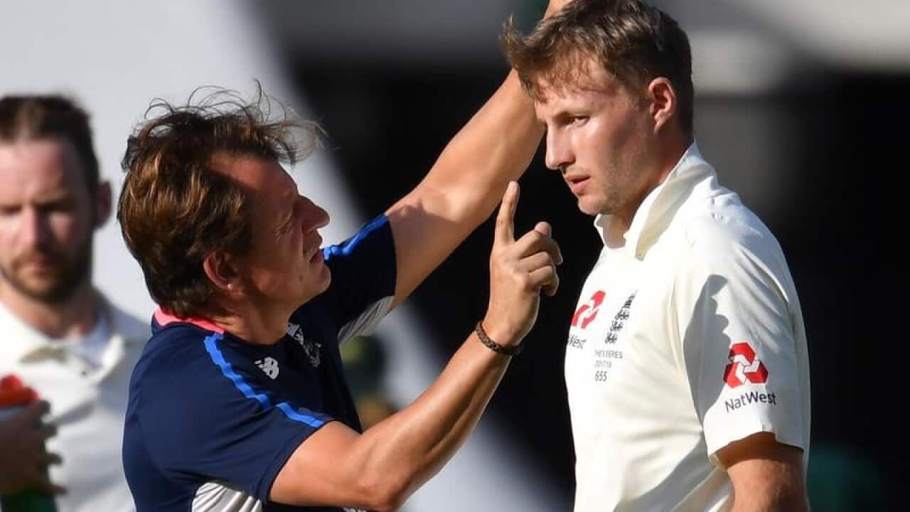 Joe Root (right) of England is examined by medical staff after.