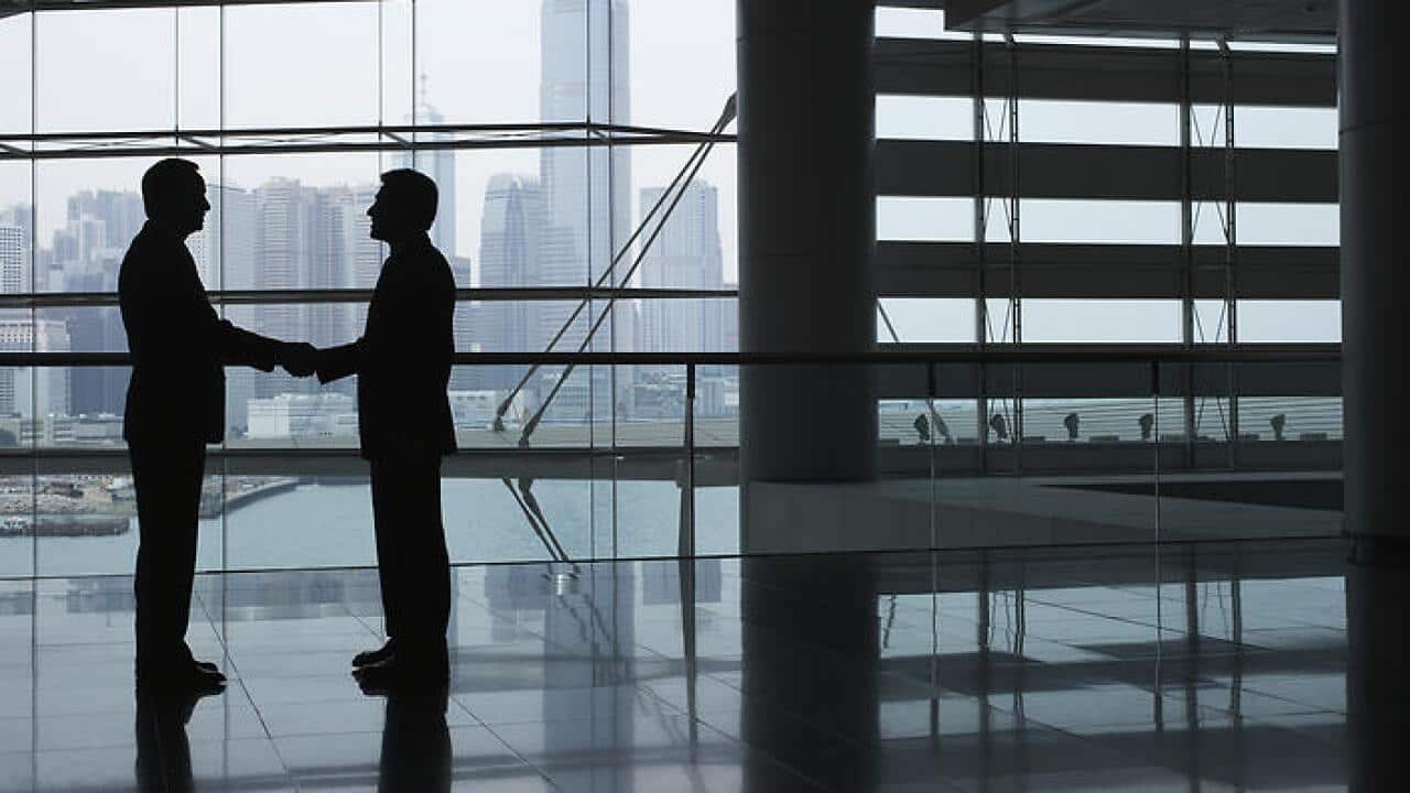 Silhouettes of two business men shaking hands