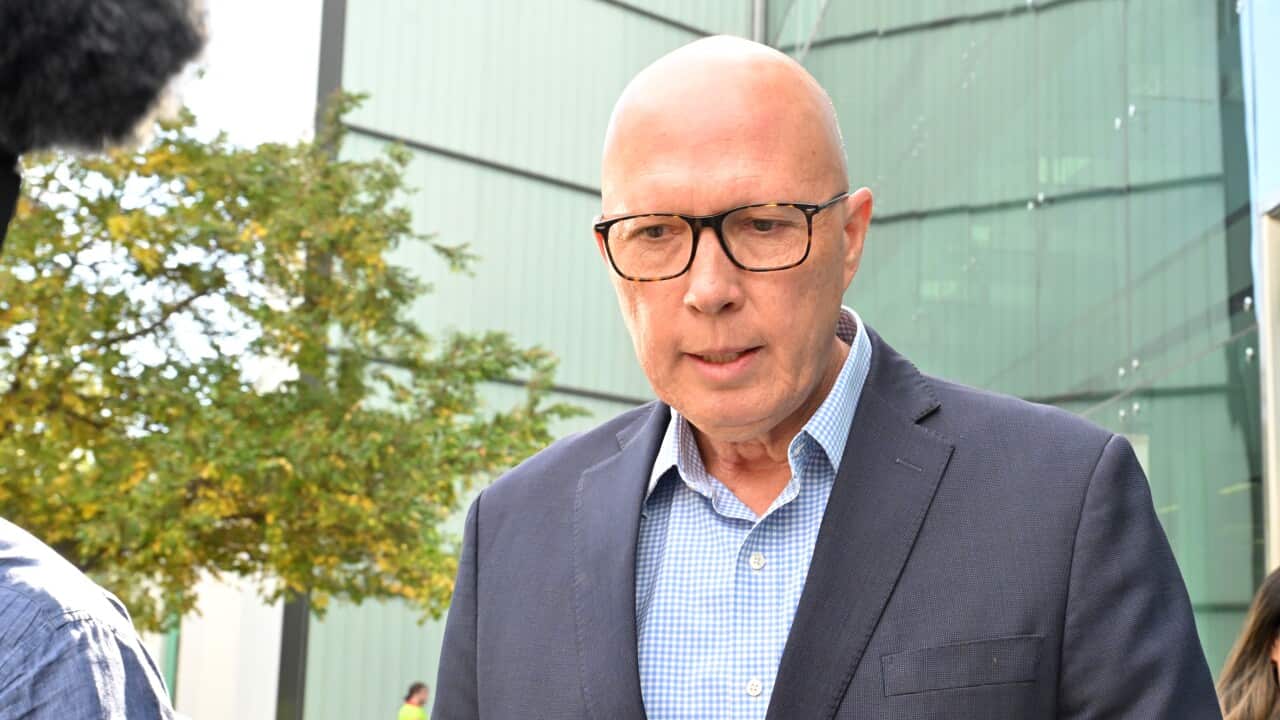 A man in a suit and glasses, looking down.