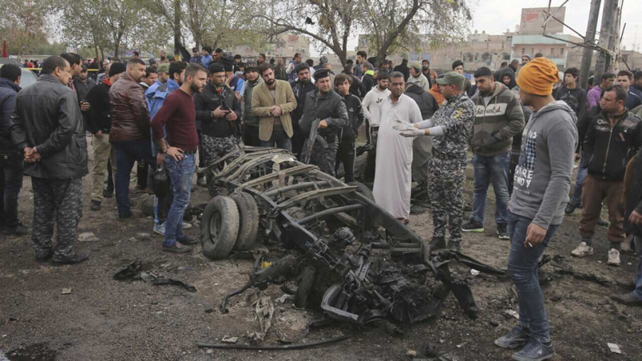 Security forces and citizens at the scene of an explosion in Baghdad