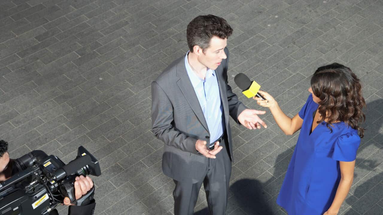 Politician talking into reporters' microphones