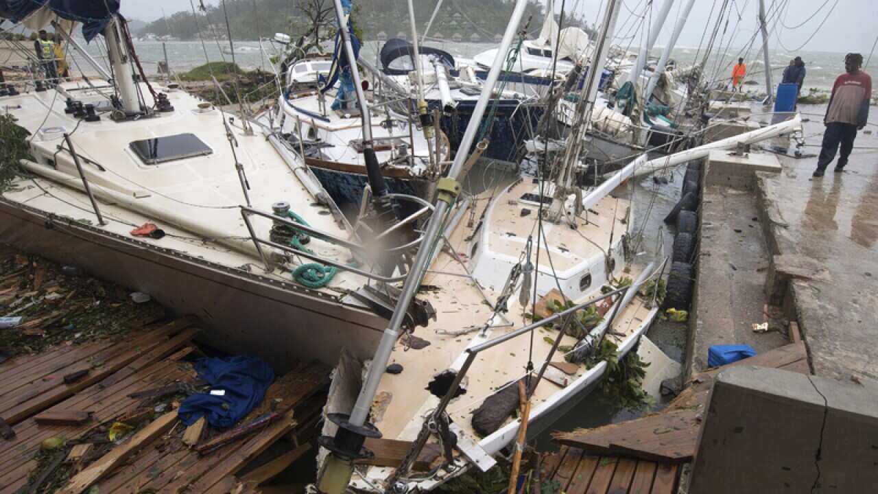 people on a dock view yachts damaged in Port Vila, Vanuatu