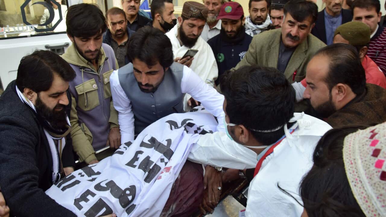 A group of men crowd around a corpse wrapped in a shroud