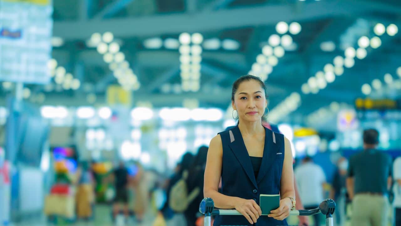 Happy Asian woman holding passport in her hand and standing in the airport.