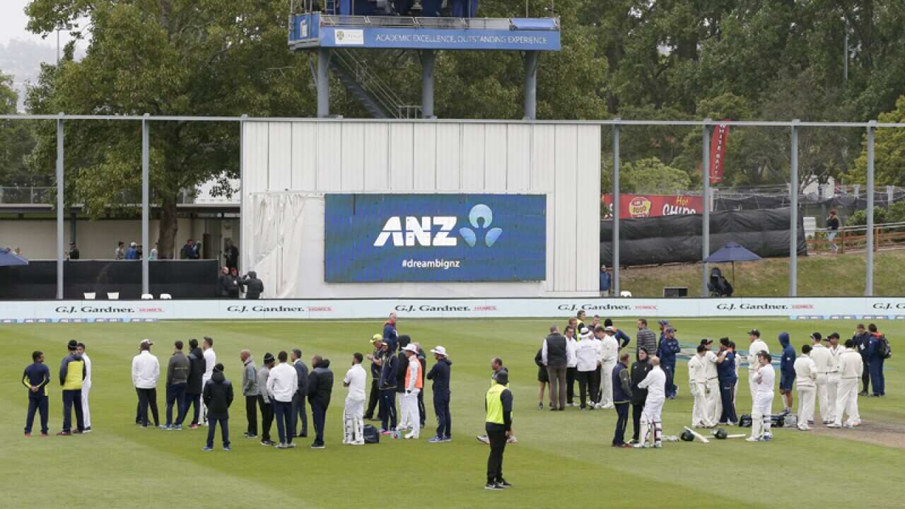 Players and officials wait on the field during a fire alarm