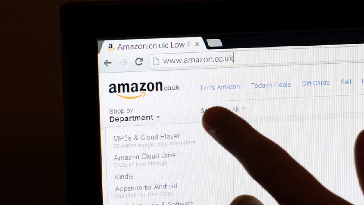 A finger points to the logo on the Amazon website.