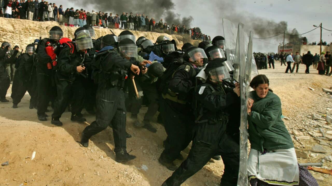 A settler struggles with Israeli officers during clashes