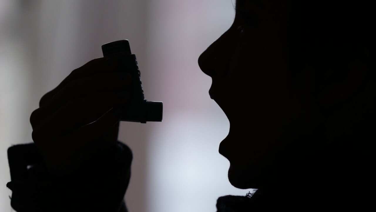 A woman holding a 'reliever' asthma inhaler, in London.