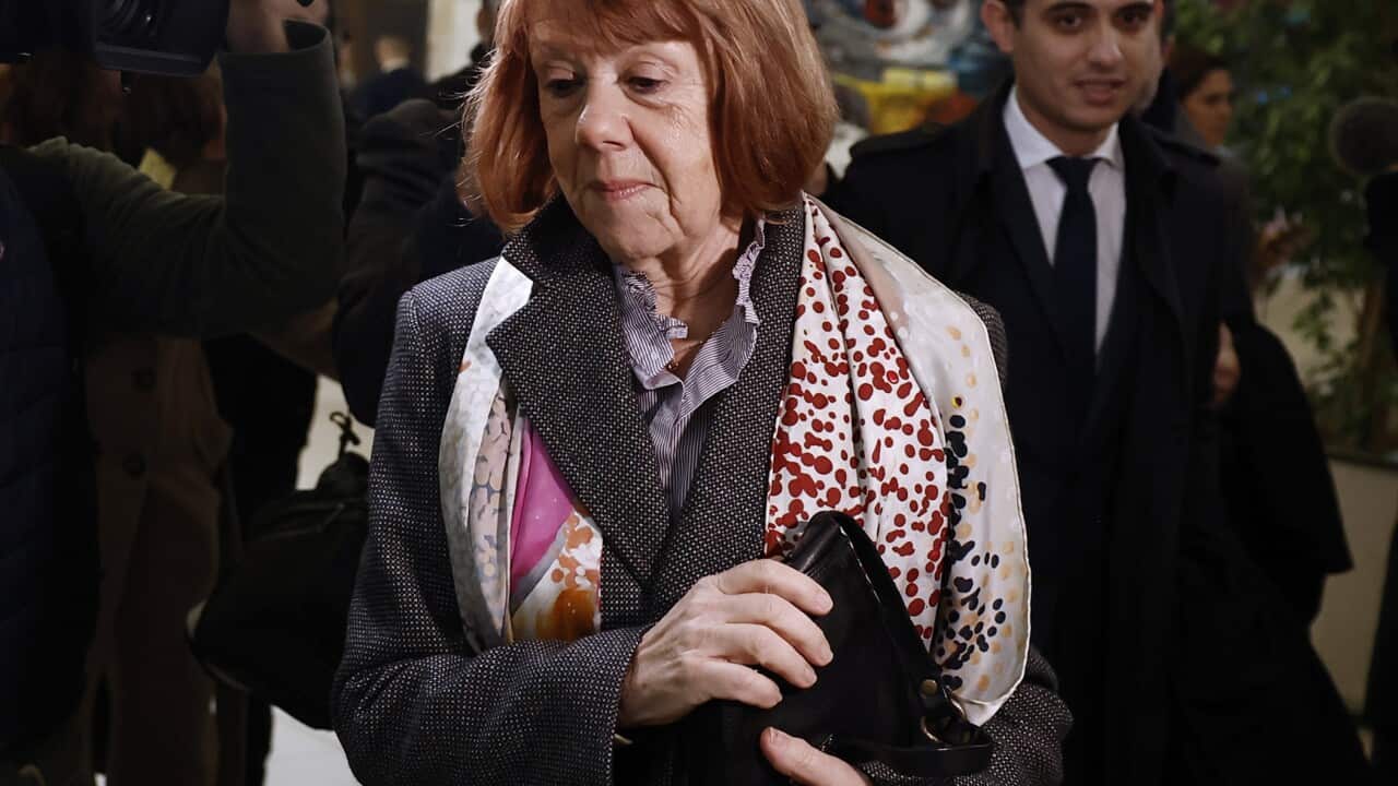 Gisele Pelicot wearing a colourful scarf while walking down a hallway.