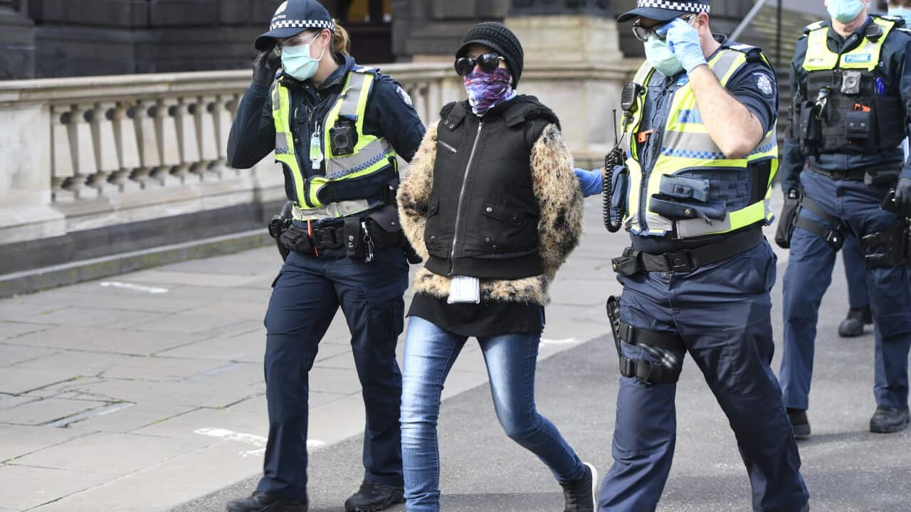 A woman is detained during an anti-mask and lockdown protest in Melbourne.