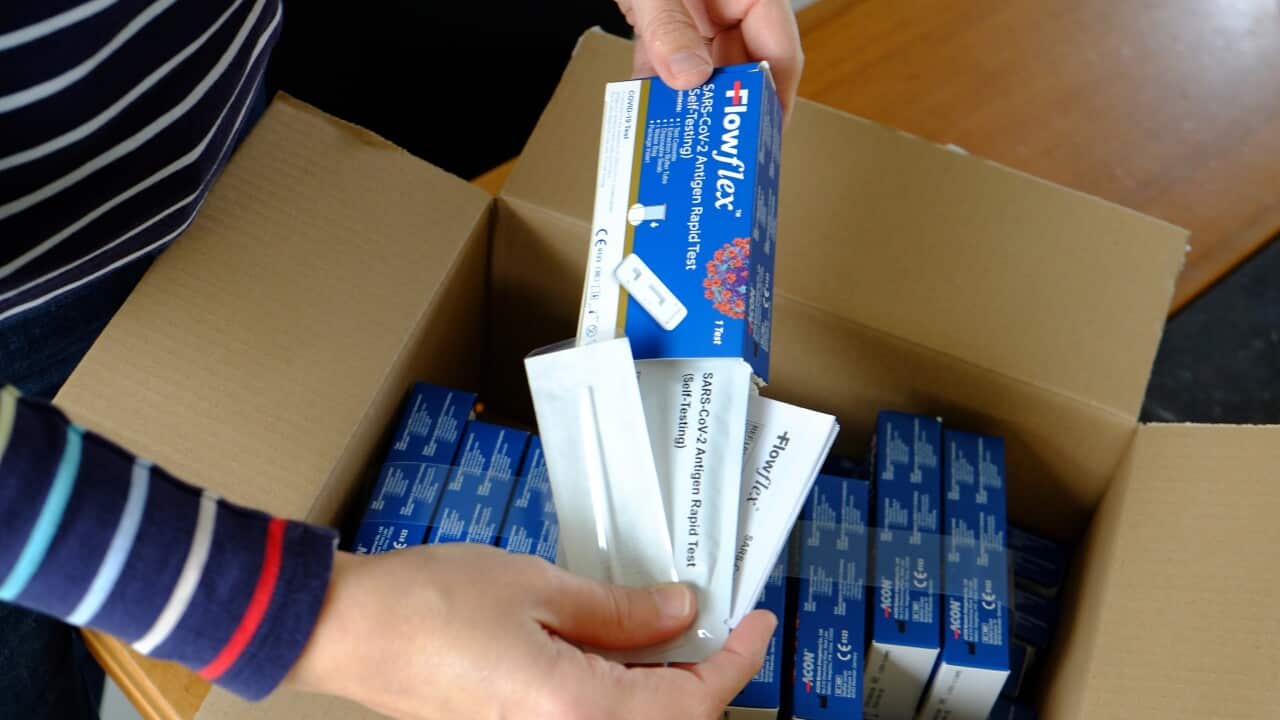 Illustration picture shows a woman receiving and unboxing a postal package with FlowFlex SARS-CoV-2 Antigen Rapid Tests for self-testing.