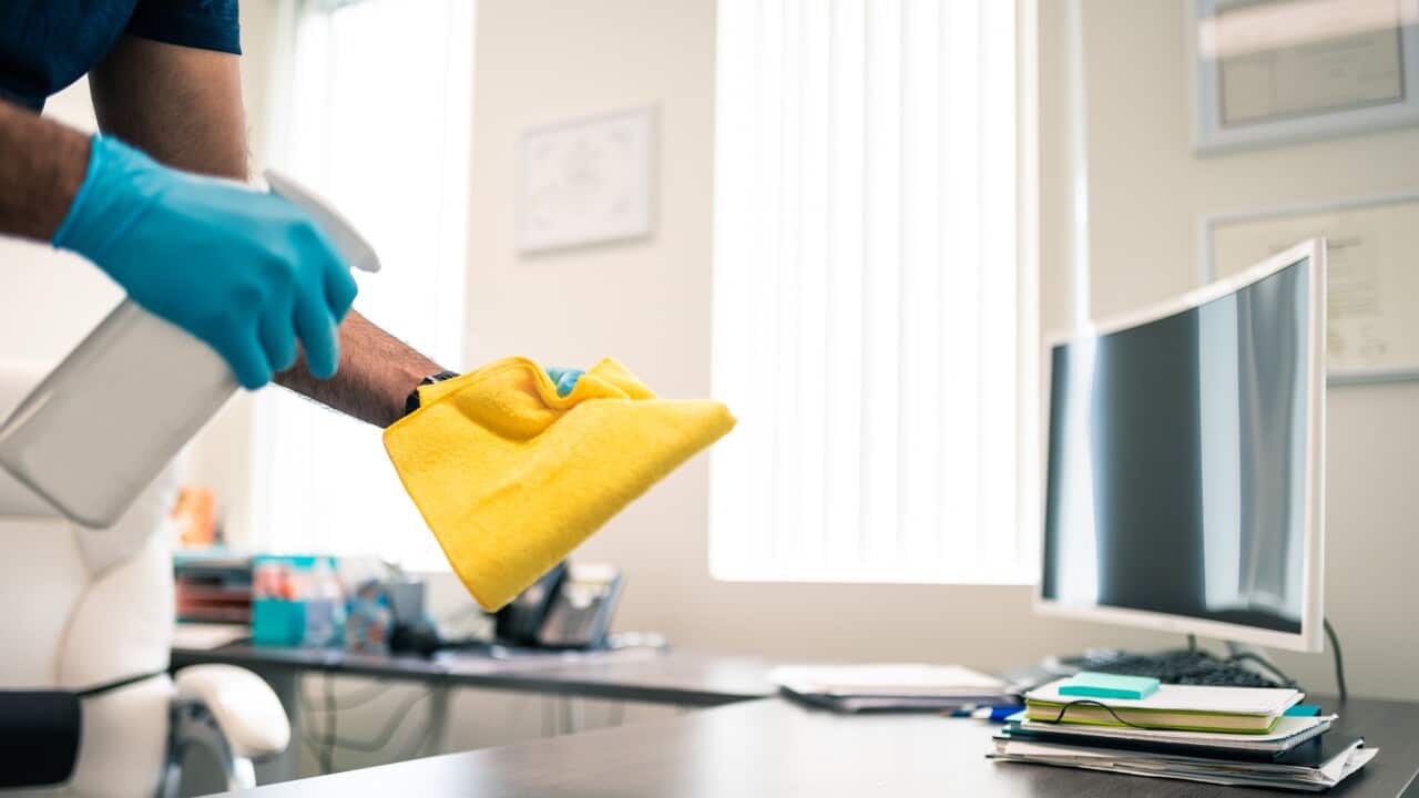 Man disinfecting an office desk