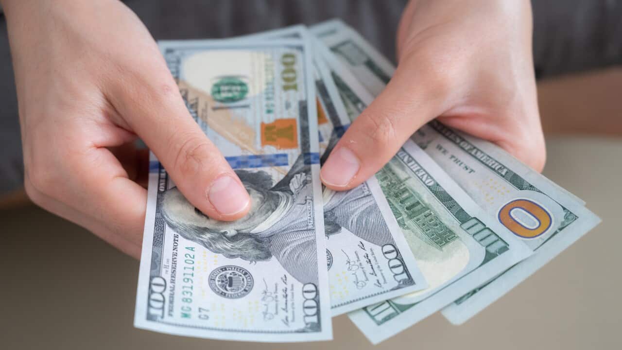 Close up of someone hands holding and counting American dollar banknotes in her hand.