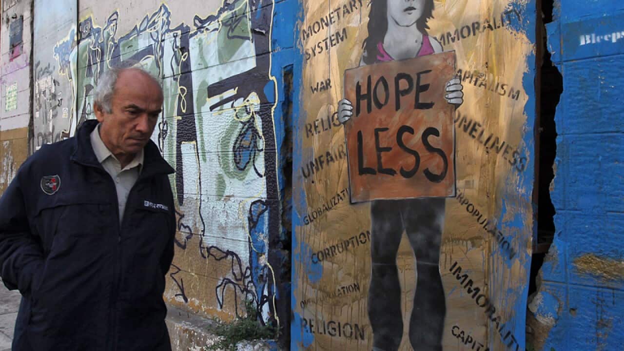 A man walking past a graffiti in central Athens