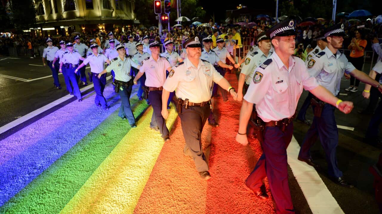 A group of police officers march past a rainbow on the ground