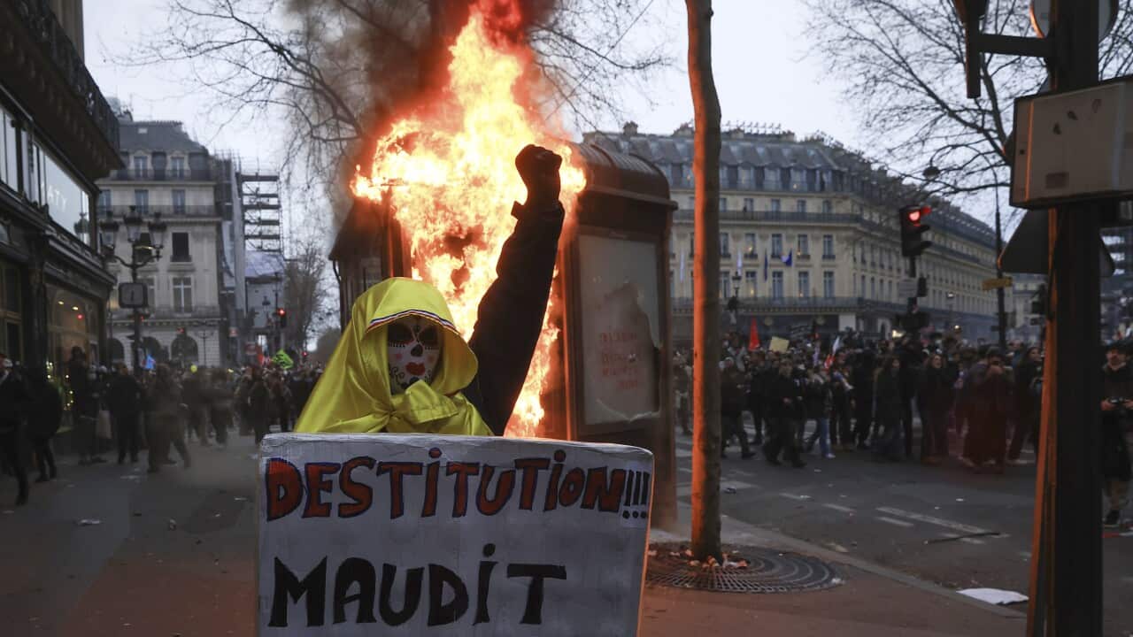 A protester holds a placard that reads, "destitution of the cursed poet " during a rally in Paris