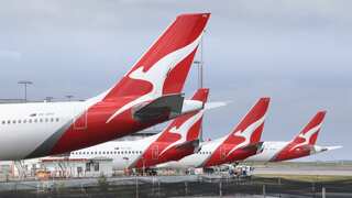 Planes with a white kangaroo on a red flag at an airport.