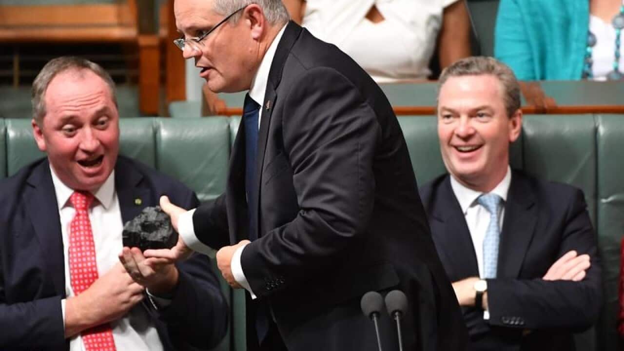 Scott Morrison hands Barnaby Joyce a lump of coal in Parliament.