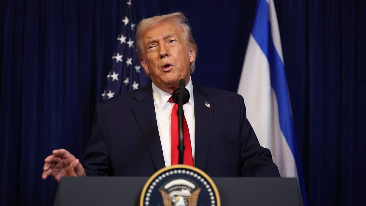 Donald Trump speaks from a podium featuring the presidential seal, positioned between the American and Israeli flags.