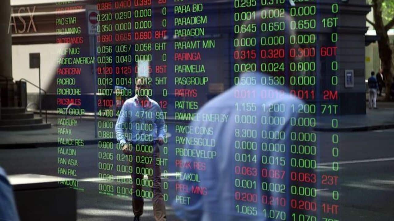 Passersby are reflected in the window of the Sydney Stock Exchange