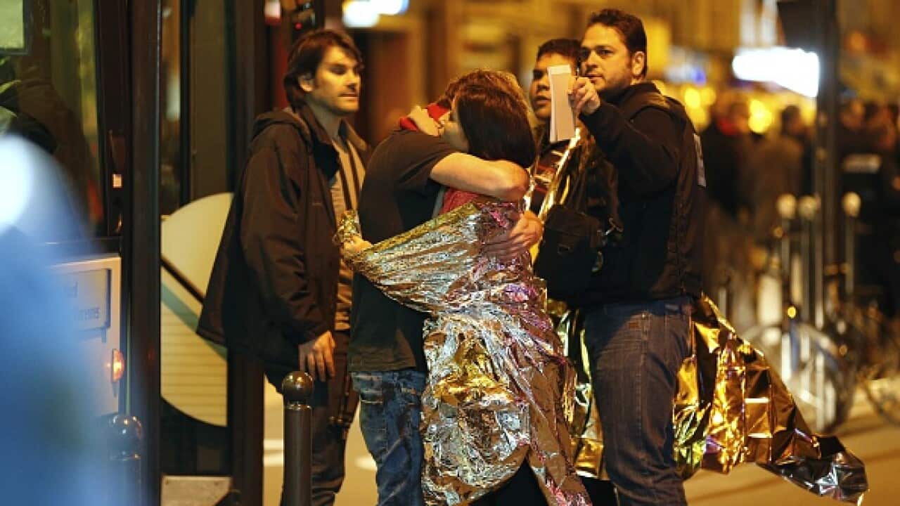 People hug each other before being evacuated by bus, near the Bataclan concert hall in central Paris, on November 14, 2015. (Photo credit should read FRANCOIS GUILLOT/AFP/Getty Images)