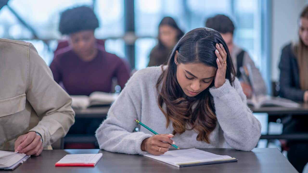 A university student has her head in her hand on desk