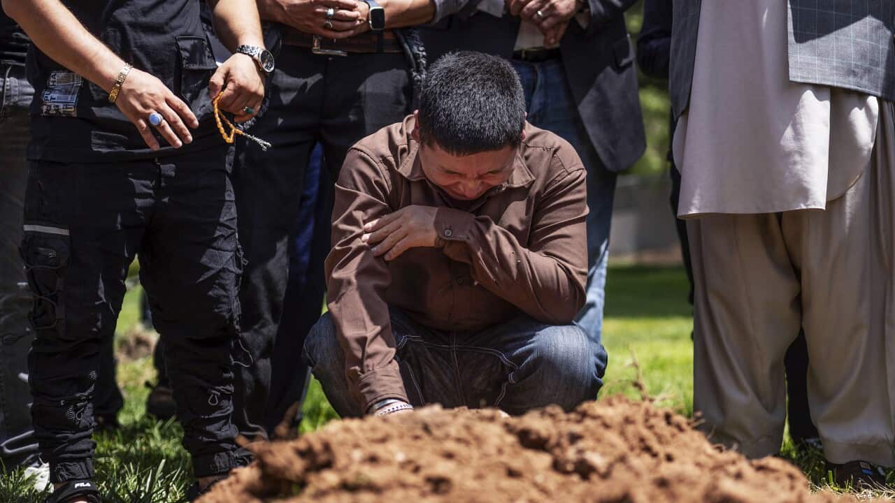A man crying in front of a grave
