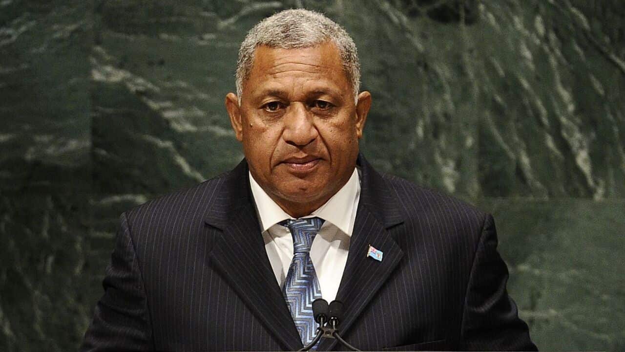 A man with short grey hair wearing a dark suit stands behind a lectern microphone at the UN General Assembly