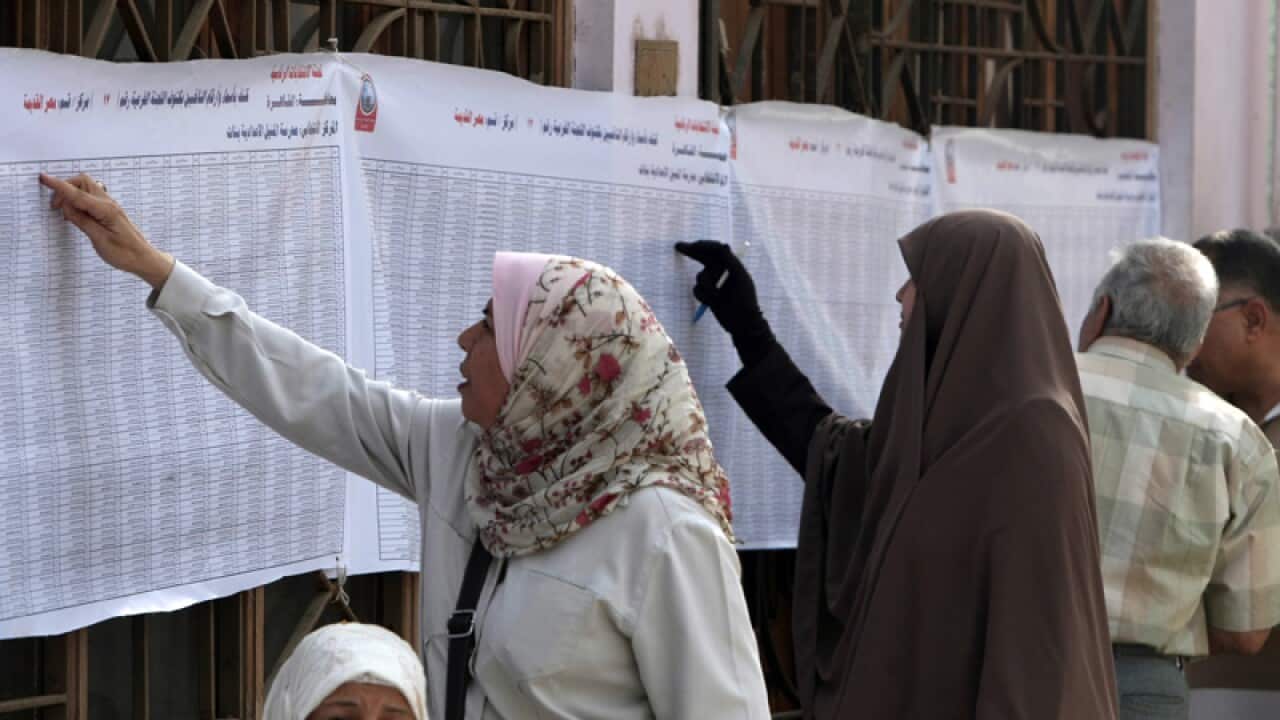 Egyptian voters search for their names on voters lists outside a polling station in Cairo