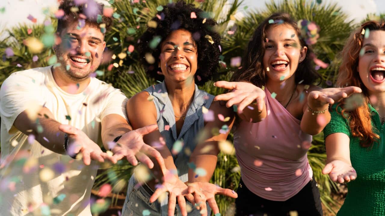 Happy friends catching colorful confetti at a summer party