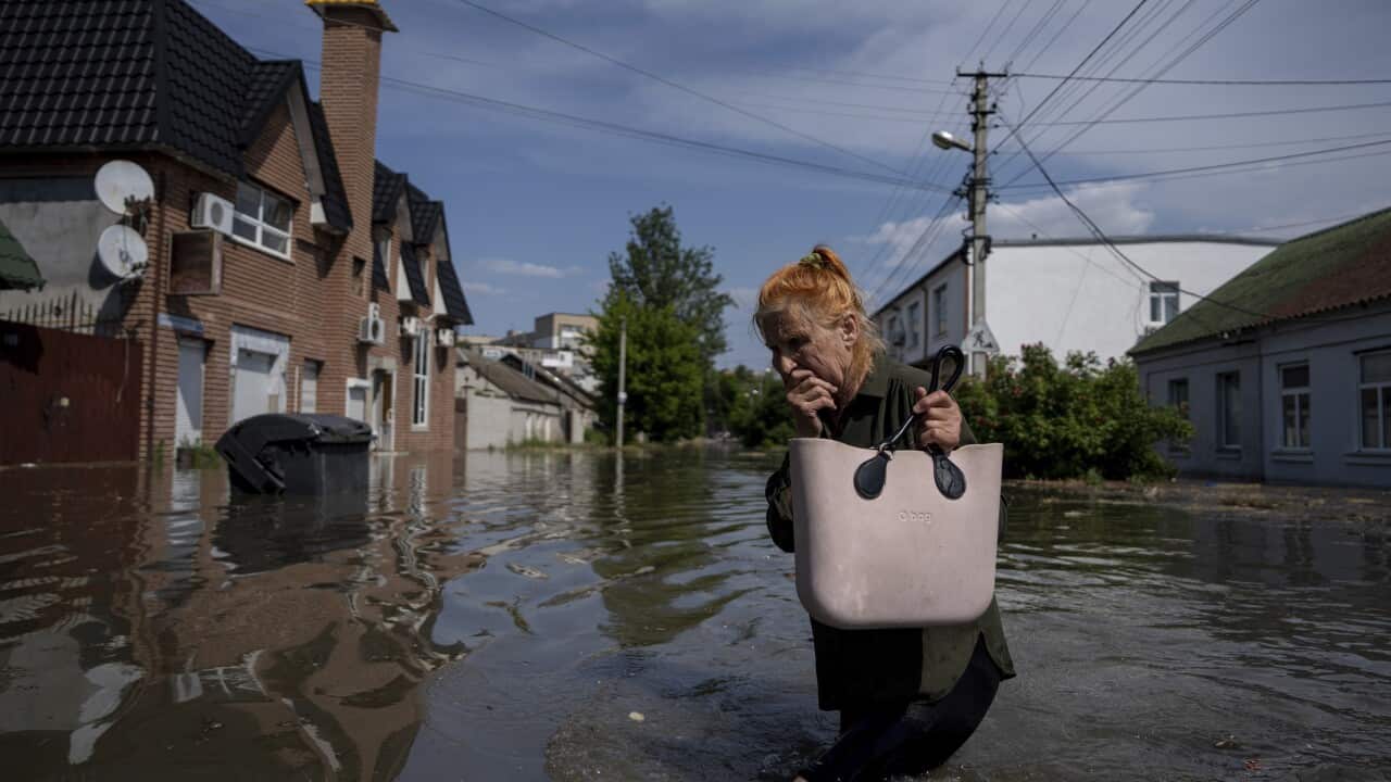 A local resident makes her way through a flooded road after the walls of the Kakhovka dam collapsed overnight, in Kherson