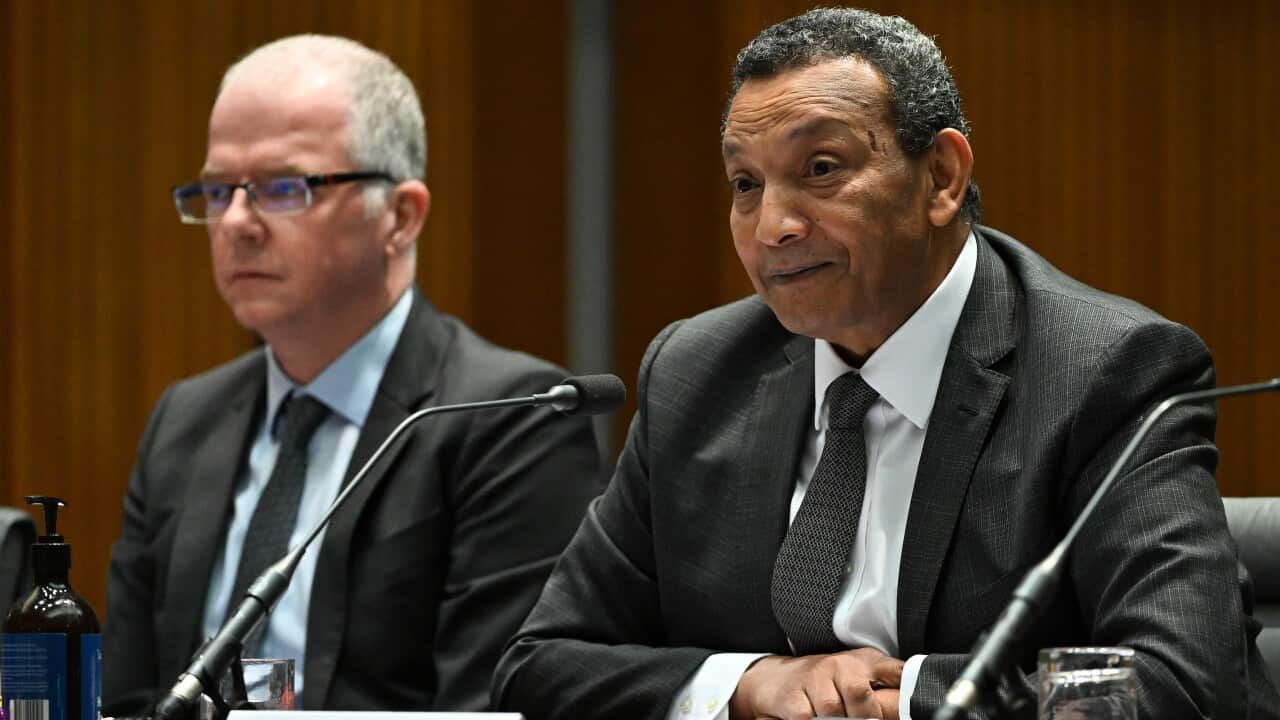 Two men wearing suits sitting next to each other