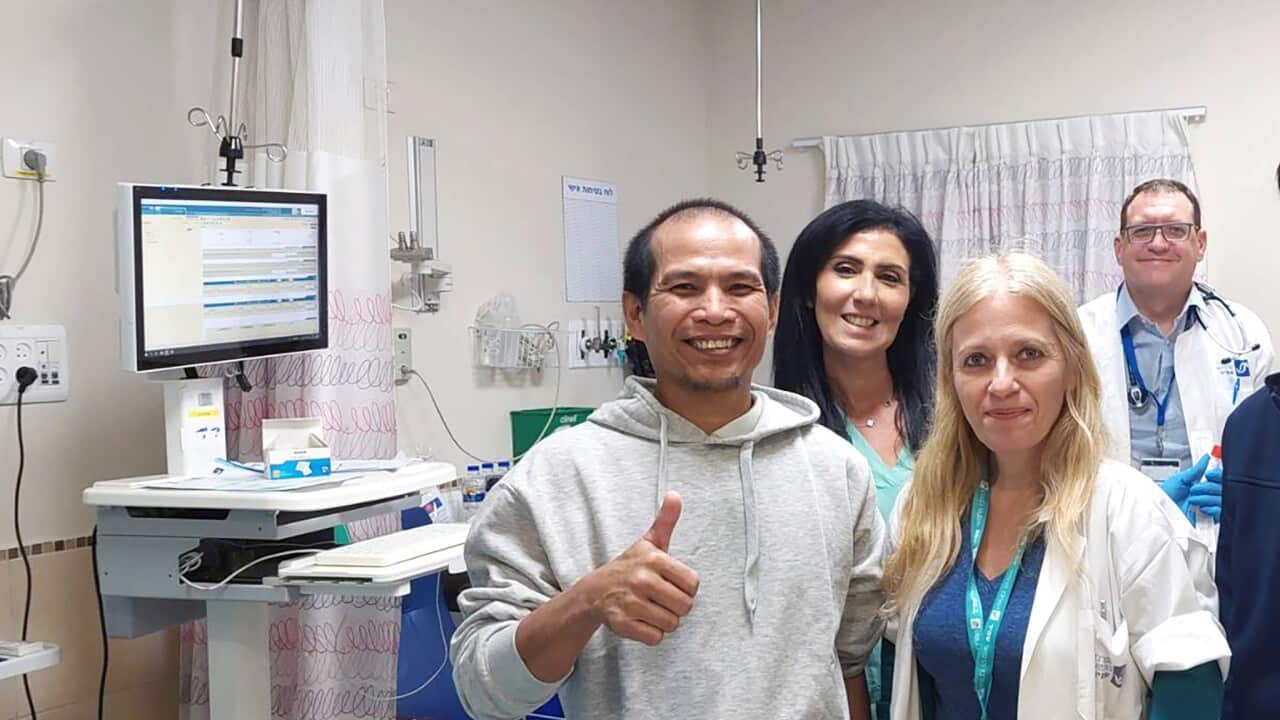 A Thai migrant worker smiles for the camera alongside Israeli medics during a medical health check
