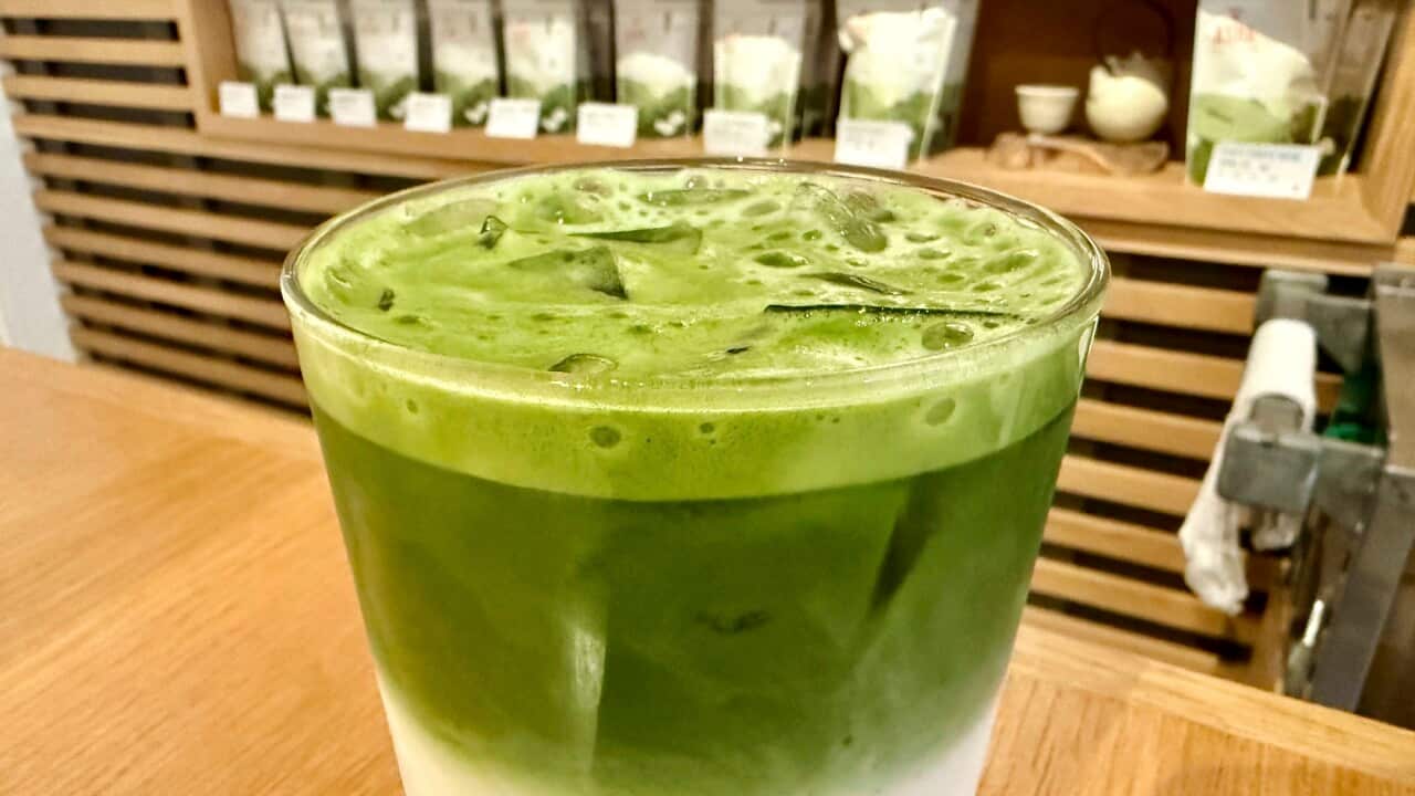 Matcha beverage with packaged matcha products on a shelf in the background.