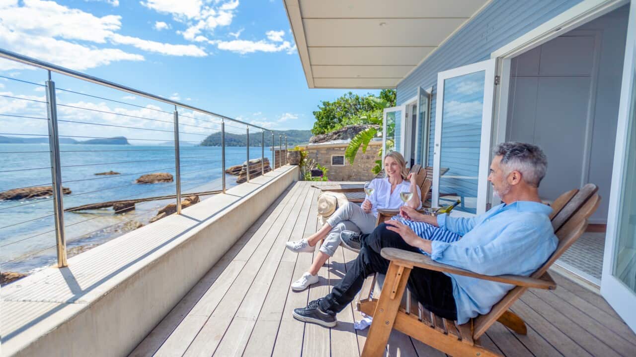 Mature couple drinking wine out on the deck in their waterfront home