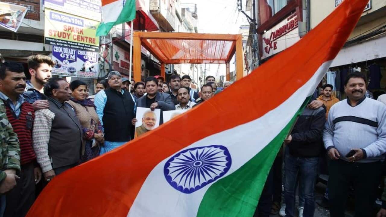Indian people wave the national flag as they celebrate the air strikes
